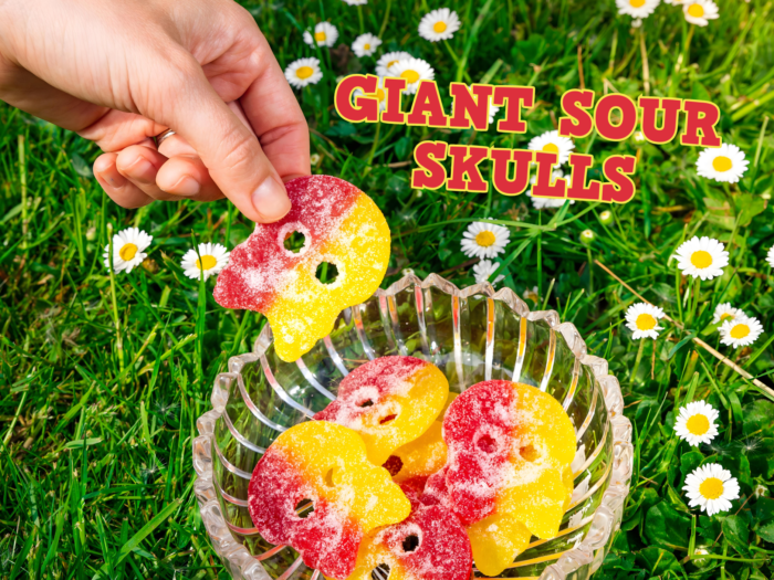 a hand holding a bowl of Bubs Sour skulls candy